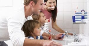 man woman and 2 children brushing teeth